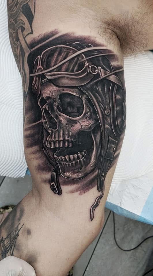 Skull tattoo on an arm, wearing a leather aviator helmet, in black and gray shading. — Whitsunday Tattooing Airlie Beach in Whitsundays, QLD