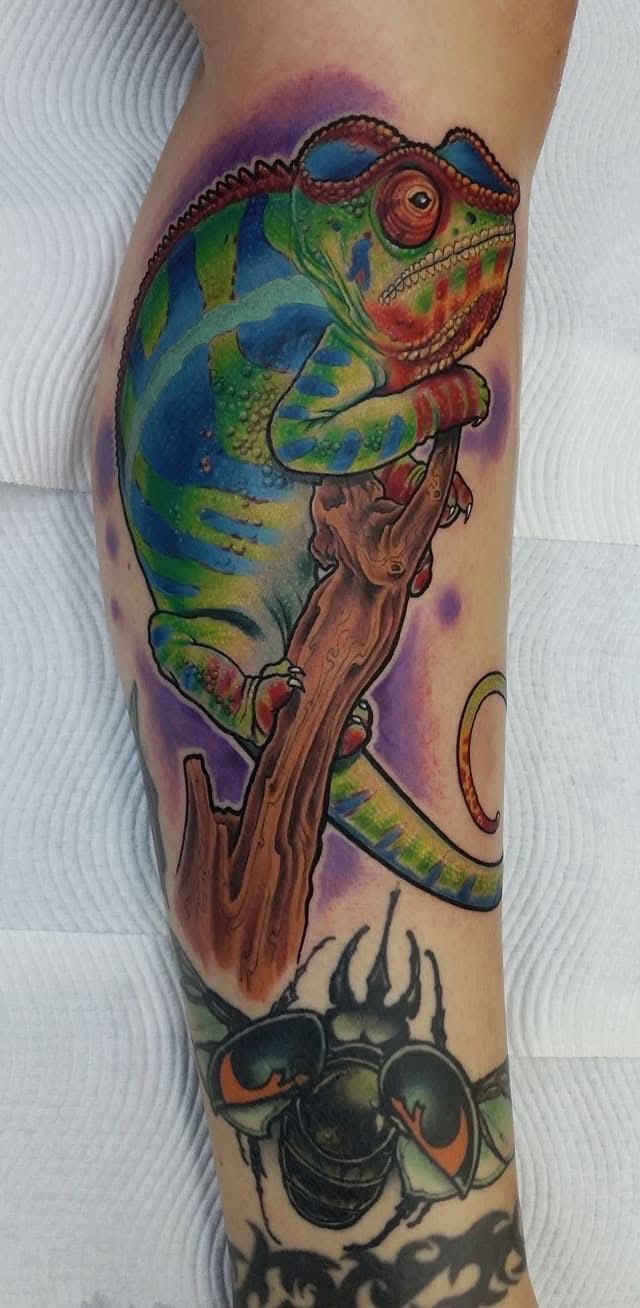 Colorful chameleon tattoo on a leg, perched on a branch, with a beetle at the bottom. — Whitsunday Tattooing Airlie Beach in Whitsundays, QLD