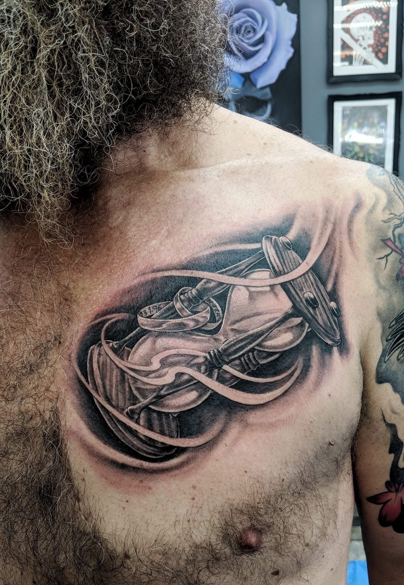 Tattoo of a black and gray steampunk-style clock on a person's chest, surrounded by swirling lines. — Whitsunday Tattooing Airlie Beach in Whitsundays, QLD