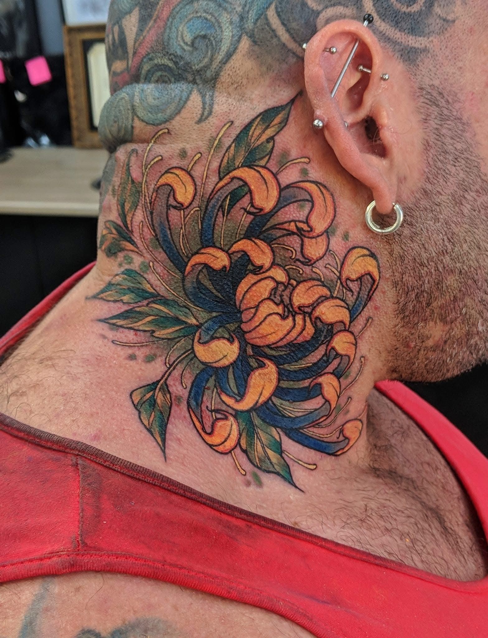 Tattoo of a Large Orange and Blue Flower With Green Leaves — Whitsunday Tattooing Airlie Beach in Airlie Beach, QLD