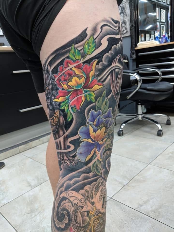 Leg tattoo with colorful flowers, dark clouds, and water waves. — Whitsunday Tattooing Airlie Beach in Whitsundays, QLD
