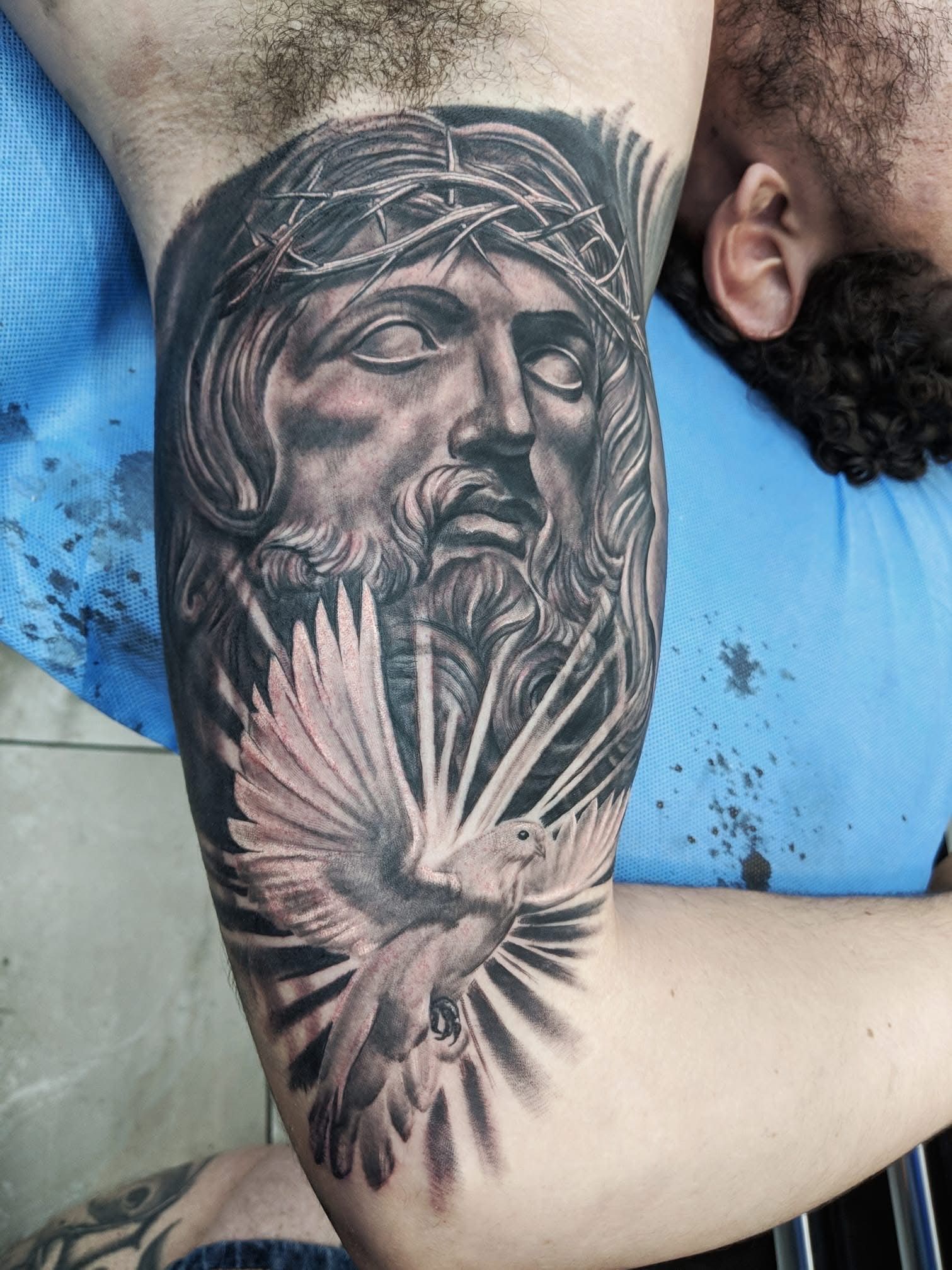 Tattoo of Jesus wearing a crown of thorns, with a dove and sun rays on arm. — Whitsunday Tattooing Airlie Beach in Whitsundays, QLD