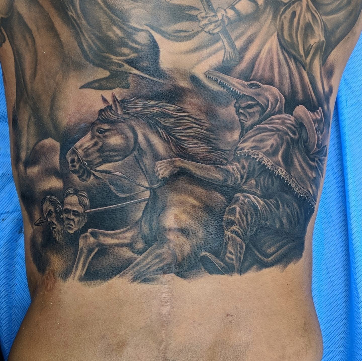 Black and gray back tattoo. A cloaked figure rides a horse, others follow in the hazy background. — Whitsunday Tattooing Airlie Beach in Whitsundays, QLD