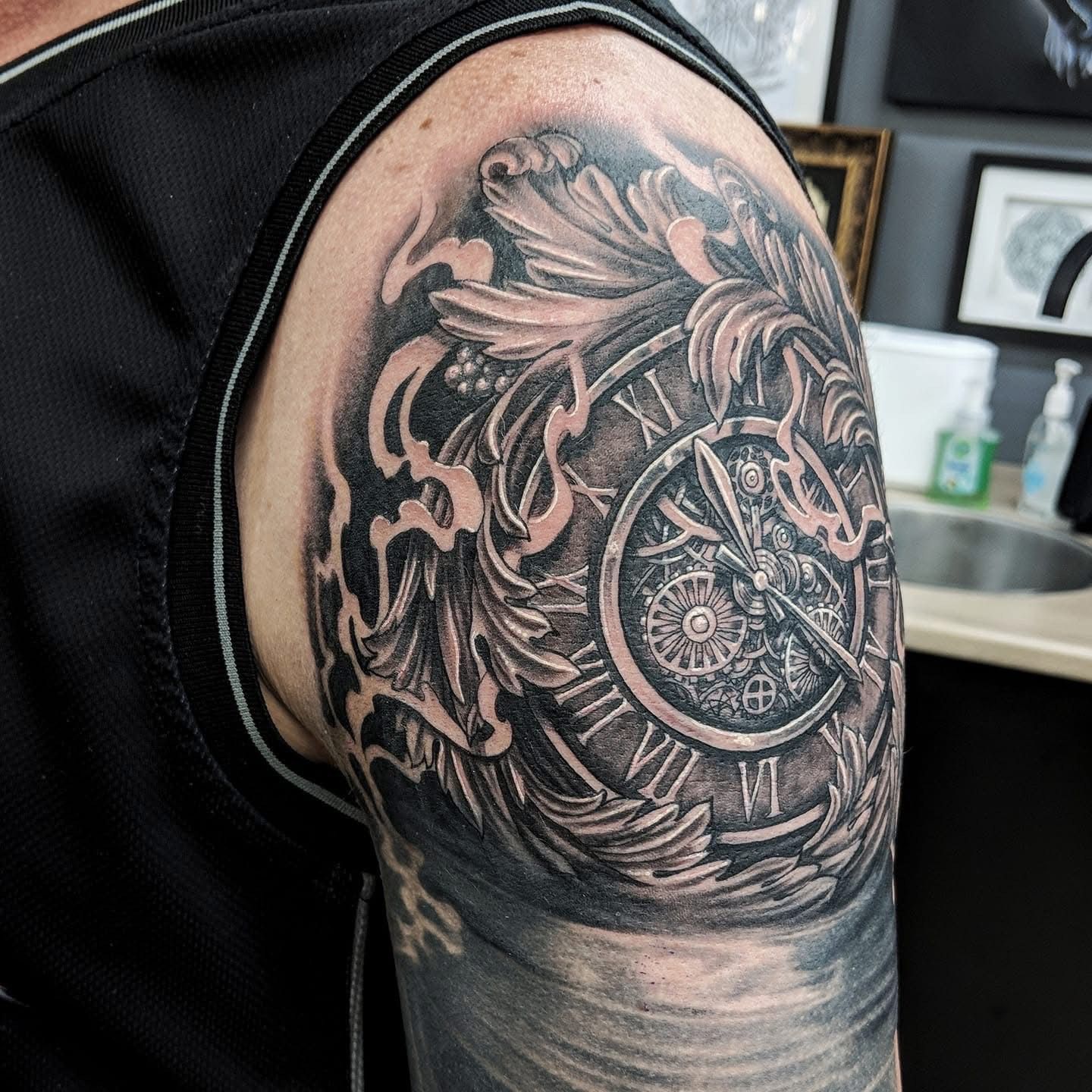 Tattoo of an ornate clock on a person's upper arm and shoulder. Black and gray shading with floral accents. — Whitsunday Tattooing Airlie Beach in Whitsundays, QLD