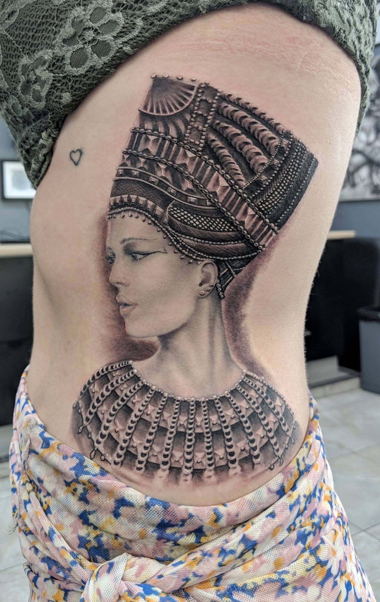 Tattoo on side of torso: bust of Nefertiti in ornate headdress and collar, in black and gray ink. — Whitsunday Tattooing Airlie Beach in Whitsundays, QLD