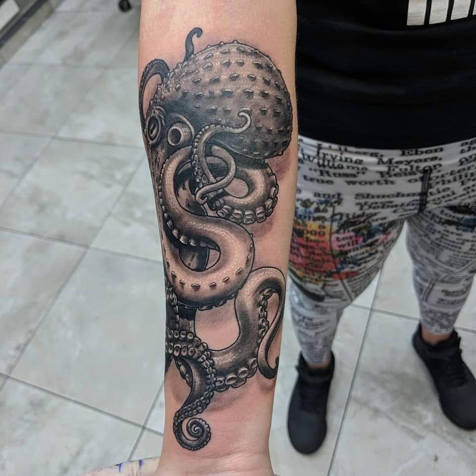 Black and gray octopus tattoo on a forearm. The octopus has many tentacles, detailed shading.