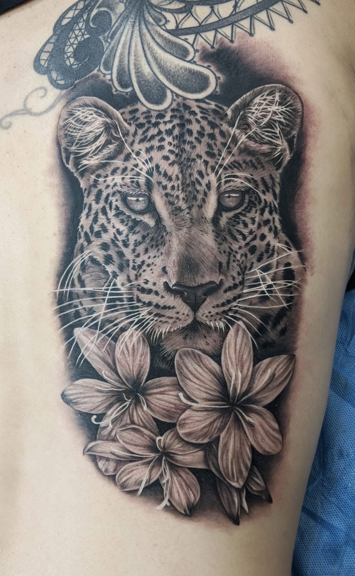 Tattoo of a leopard's face and flowers in black and gray, on a person's back. — Whitsunday Tattooing Airlie Beach in Whitsundays, QLD