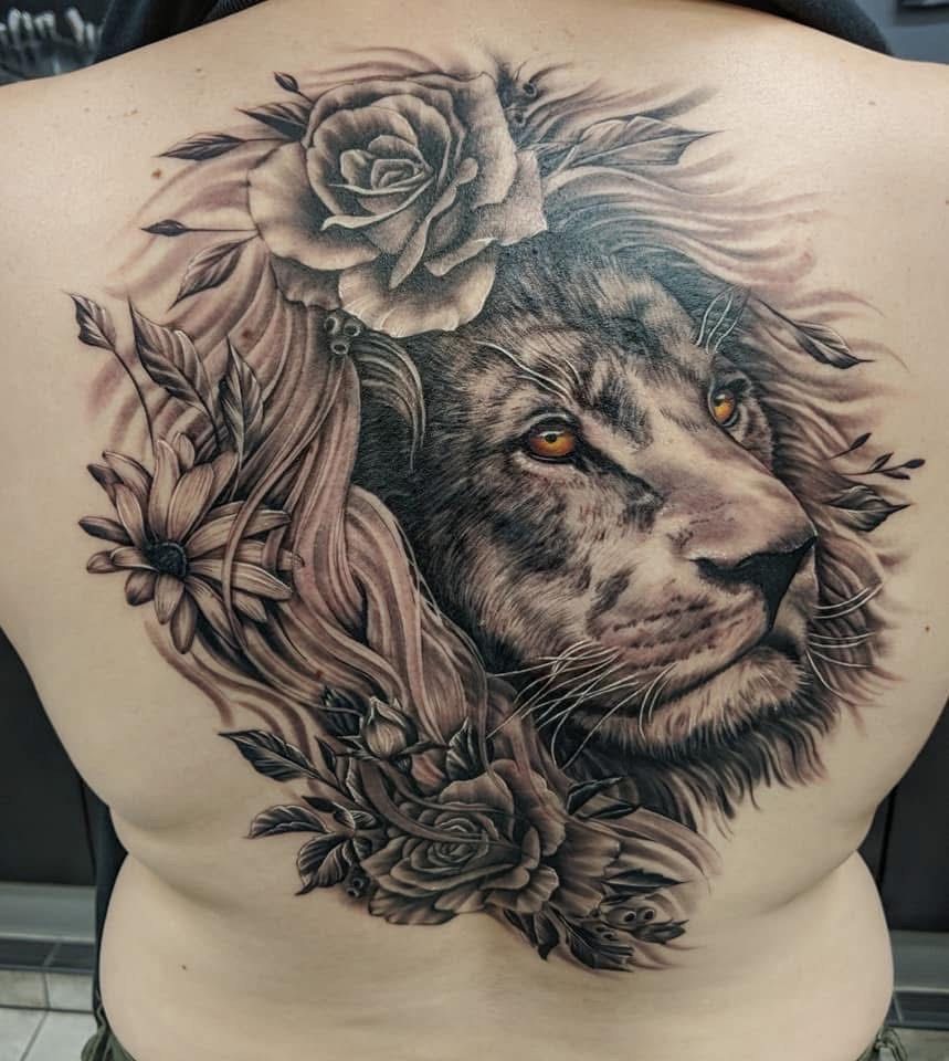 Tattoo of a lion's head with floral elements in shades of gray on a person's back. — Whitsunday Tattooing Airlie Beach in Whitsundays, QLD