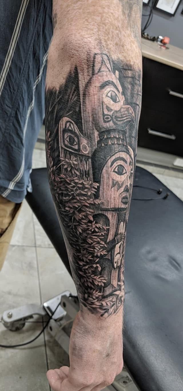 Black and grey forearm tattoo with Northwest Coast Native American imagery, including totems and natural elements. — Whitsunday Tattooing Airlie Beach in Whitsundays, QLD