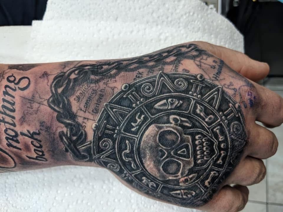 Hand tattoo with skull, circular design, and chain; map background. — Whitsunday Tattooing Airlie Beach in Whitsundays, QLD
