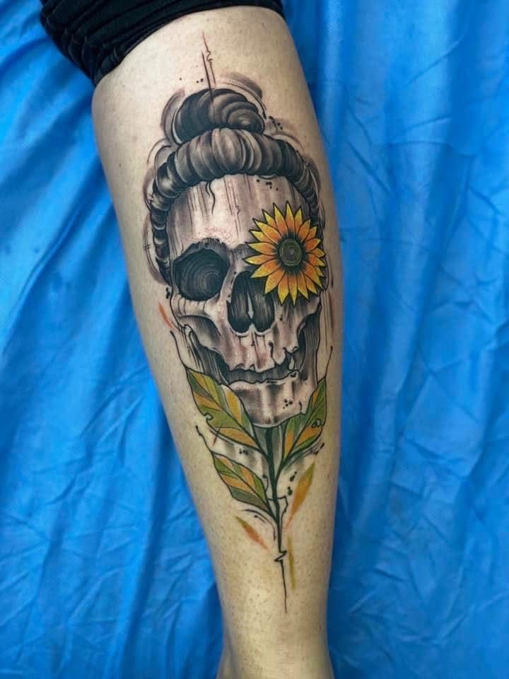 Skull tattoo with a sunflower eye and leafy stem, inked on a leg. — Whitsunday Tattooing Airlie Beach in Whitsundays, QLD