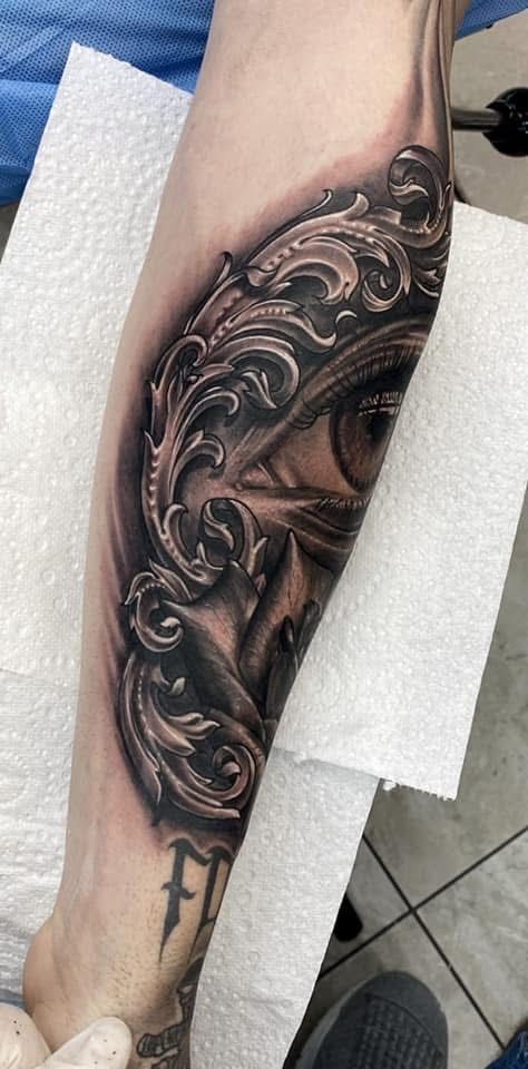 Tattoo of an eye behind ornate, detailed scrollwork on a forearm. — Whitsunday Tattooing Airlie Beach in Whitsundays, QLD