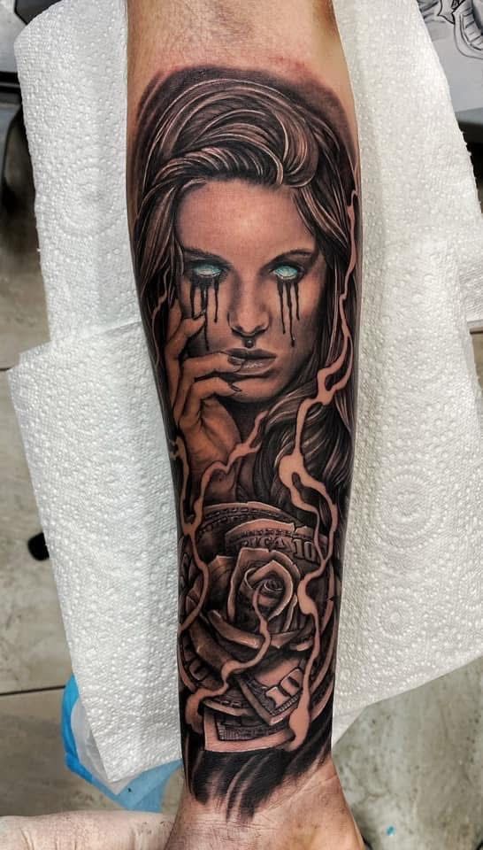Tattoo of a woman with tears, a rose, and stylized smoke on a forearm; in black and gray. — Whitsunday Tattooing Airlie Beach in Whitsundays, QLD