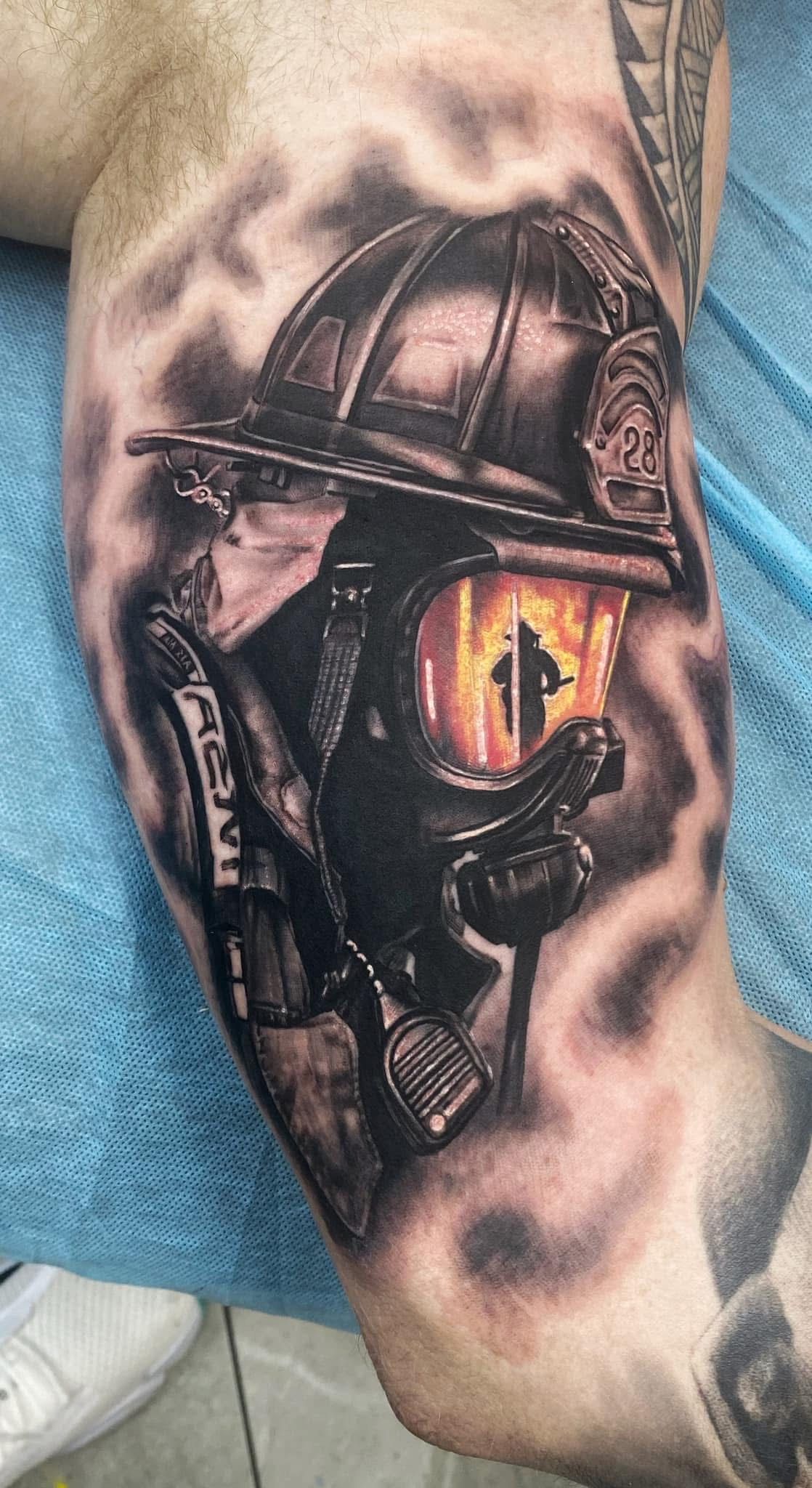 Tattoo of a firefighter in a helmet and mask with a fiery glow inside the mask, surrounded by smoky shading. — Whitsunday Tattooing Airlie Beach in Whitsundays, QLD