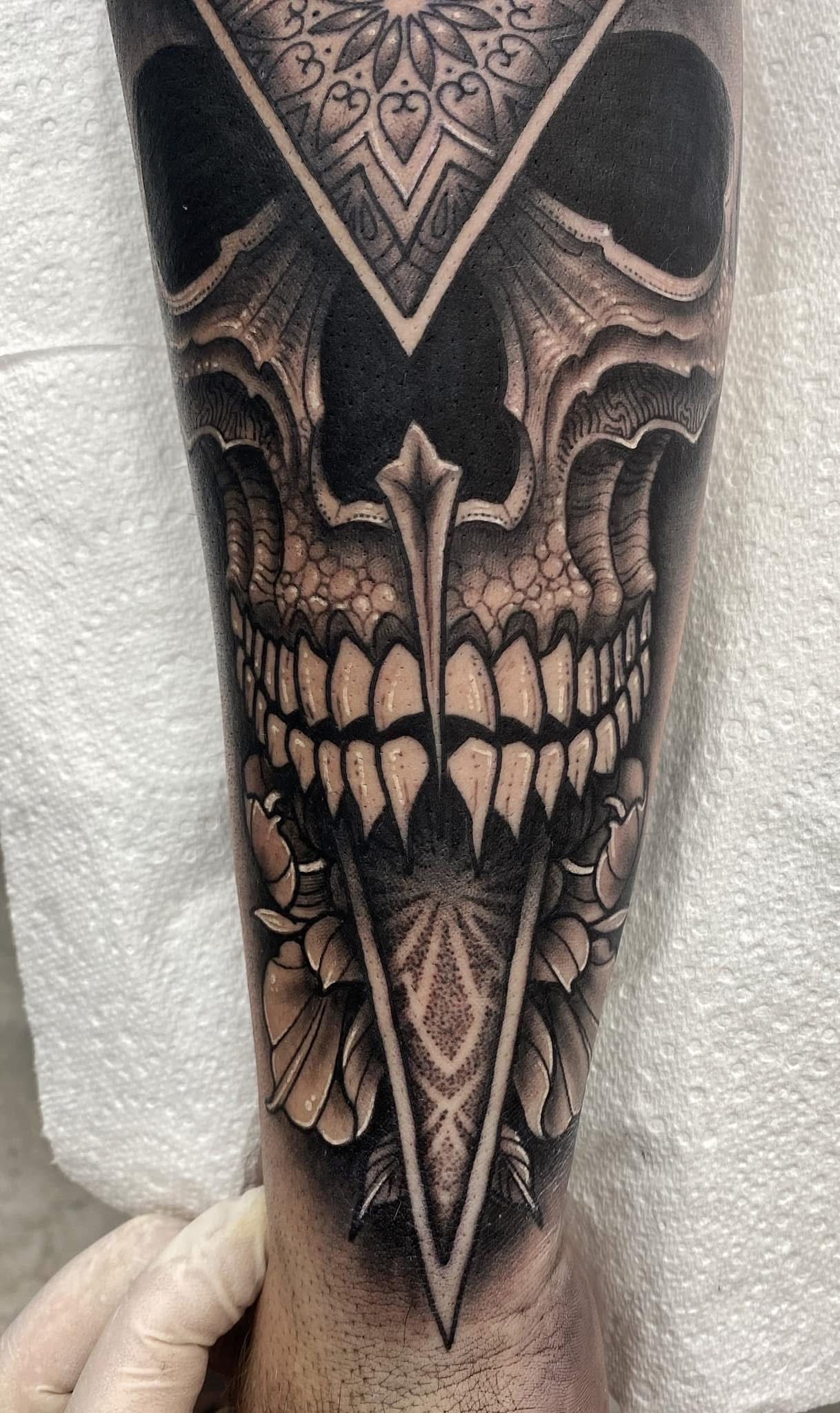 Skull tattoo on a forearm; black and gray shading with geometric and floral accents. — Whitsunday Tattooing Airlie Beach in Whitsundays, QLD