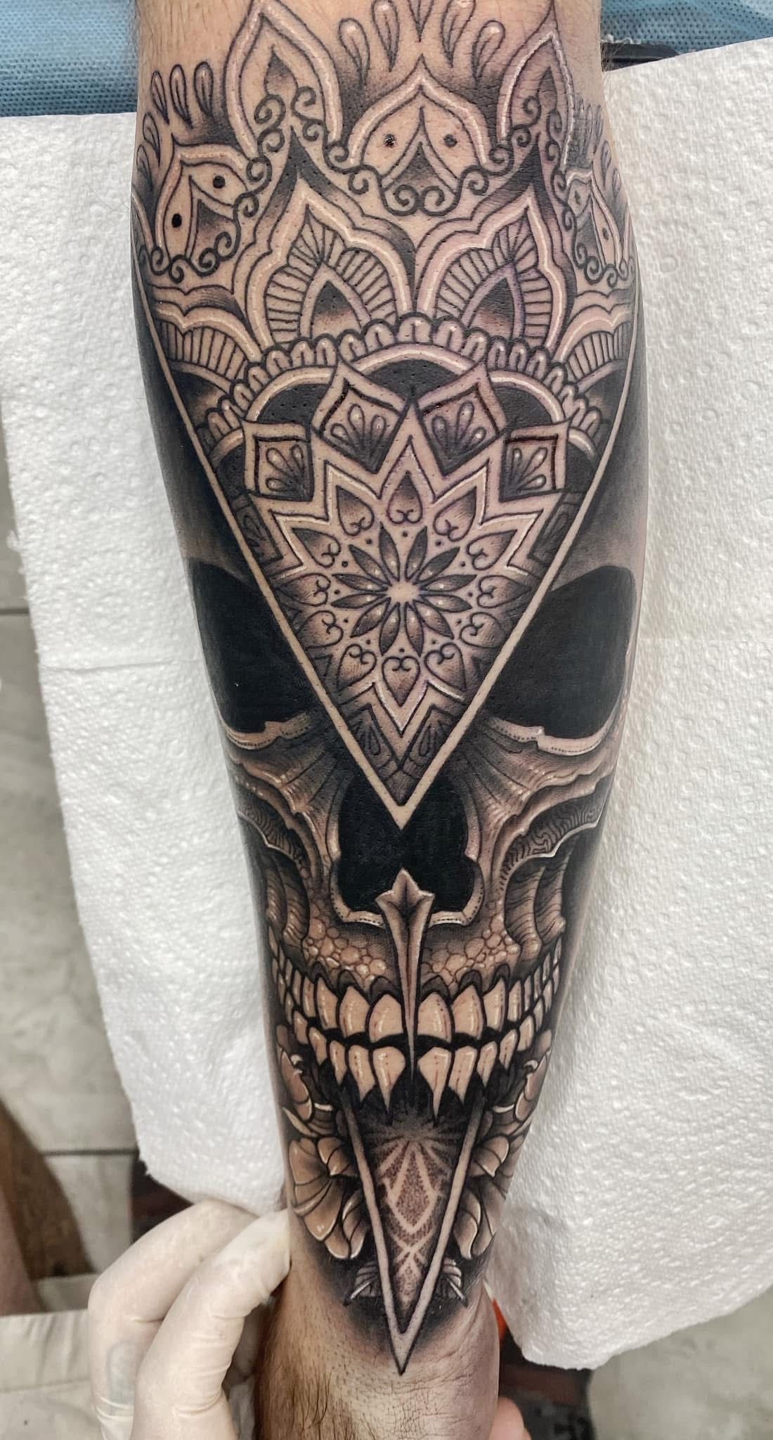 Tattoo of a skull and ornamental design on a forearm, mostly black and grey ink. — Whitsunday Tattooing Airlie Beach in Whitsundays, QLD