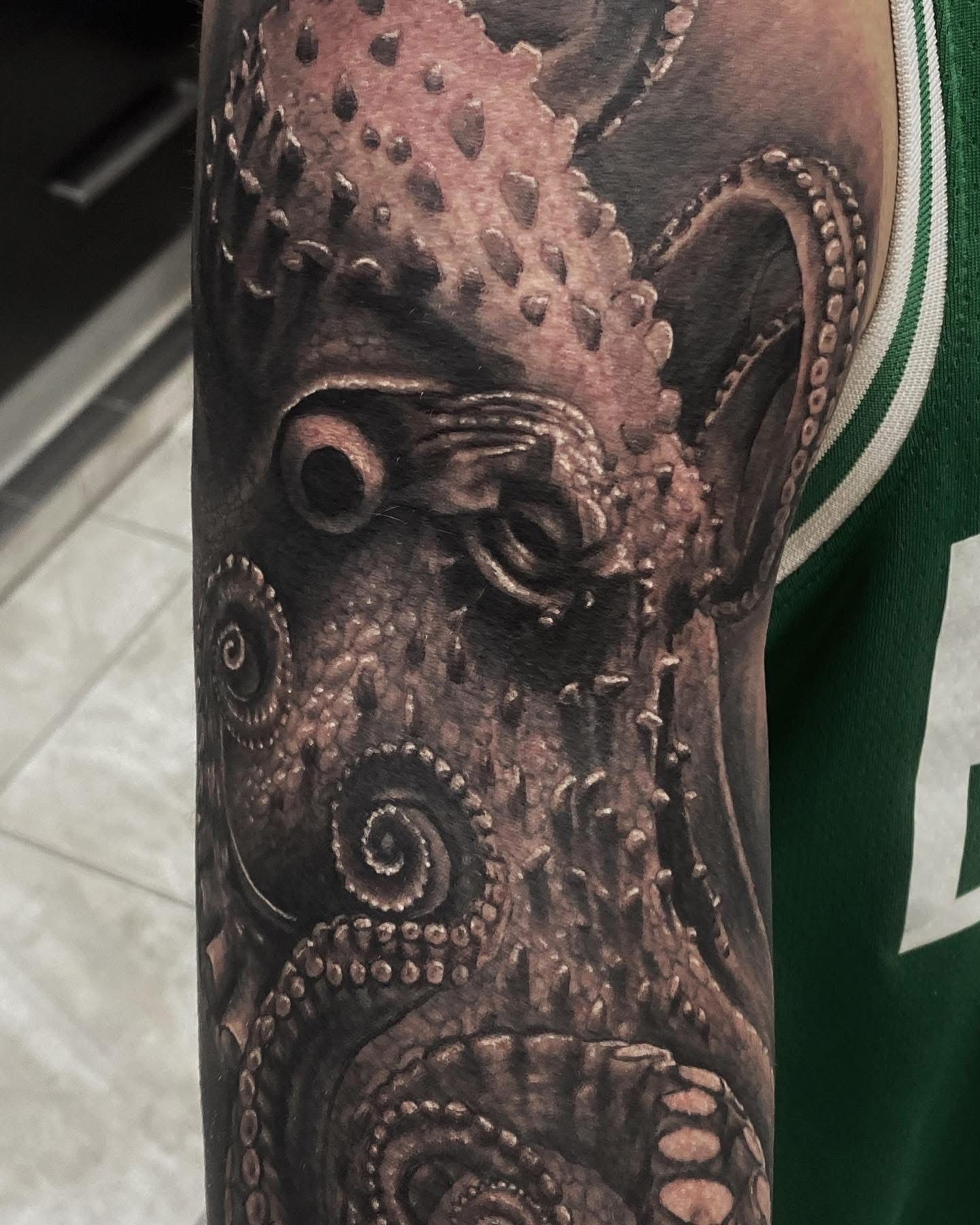 Detailed black and gray octopus tattoo on a person's upper arm, with textures and shading. — Whitsunday Tattooing Airlie Beach in Whitsundays, QLD