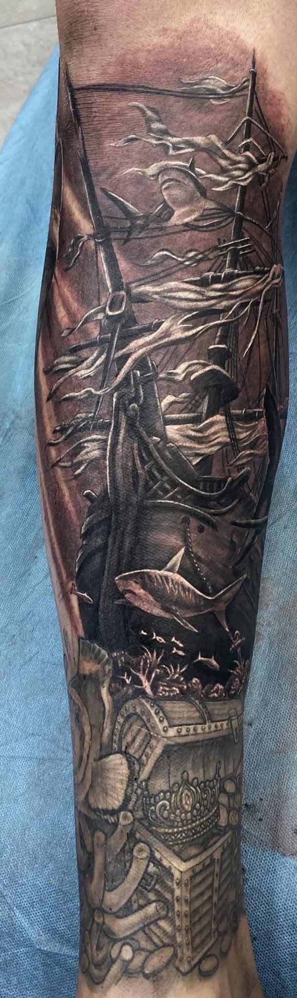 Arm with a detailed, dark tattoo. The tattoo wraps around the arm, showing intricate designs in a style that resembles a sculpture. — Whitsunday Tattooing Airlie Beach in Whitsundays, QLD