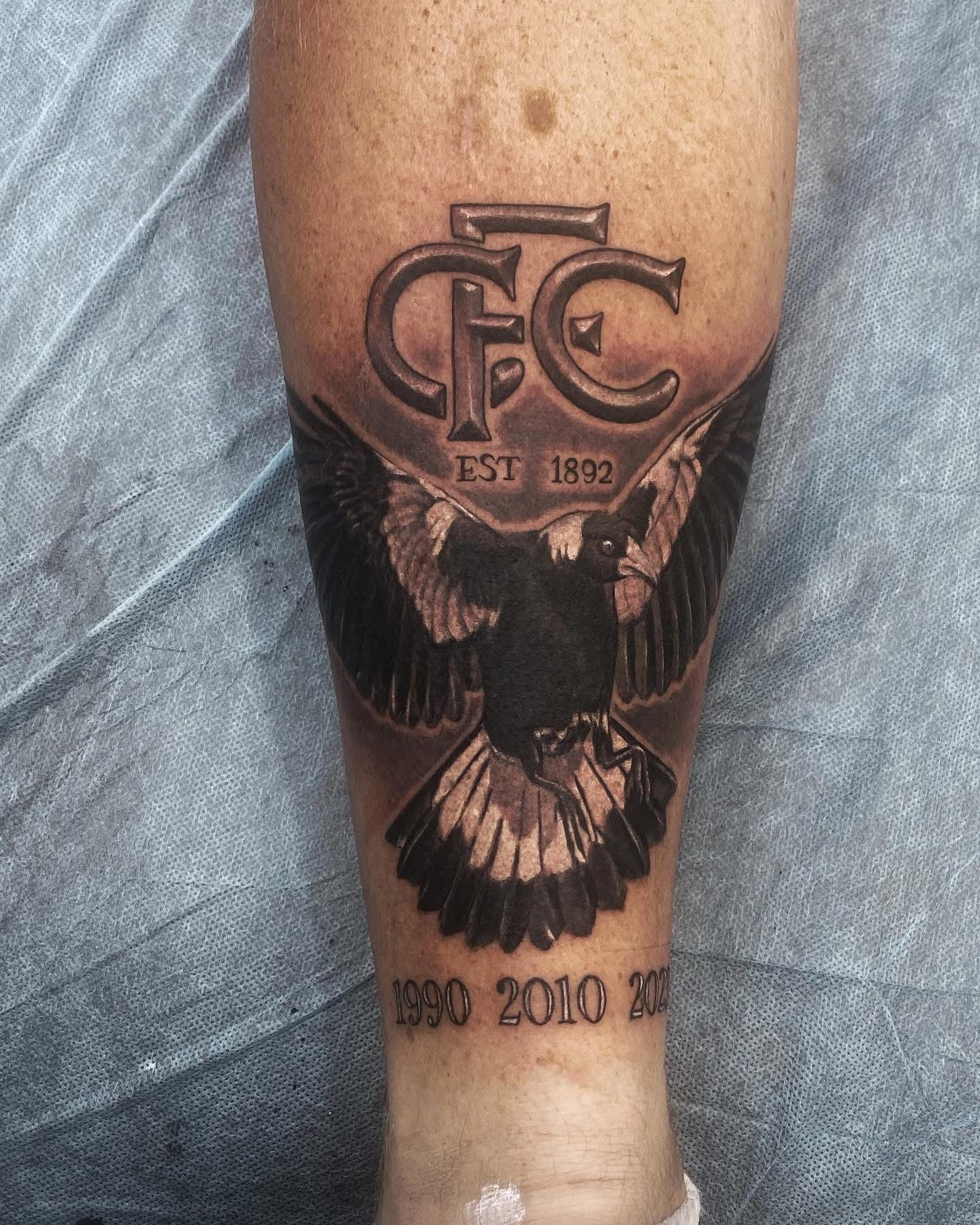 Tattoo of a black and white magpie bird with wings spread, and the Carlton Football Club logo on a leg. — Whitsunday Tattooing Airlie Beach in Whitsundays, QLD