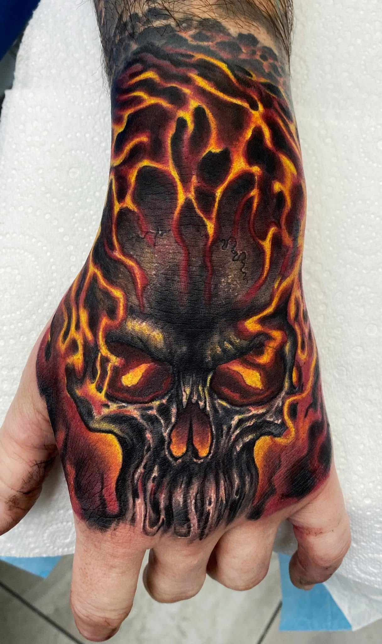 Hand tattoo: skull with fiery orange and red lava design. — Whitsunday Tattooing Airlie Beach in Whitsundays, QLD