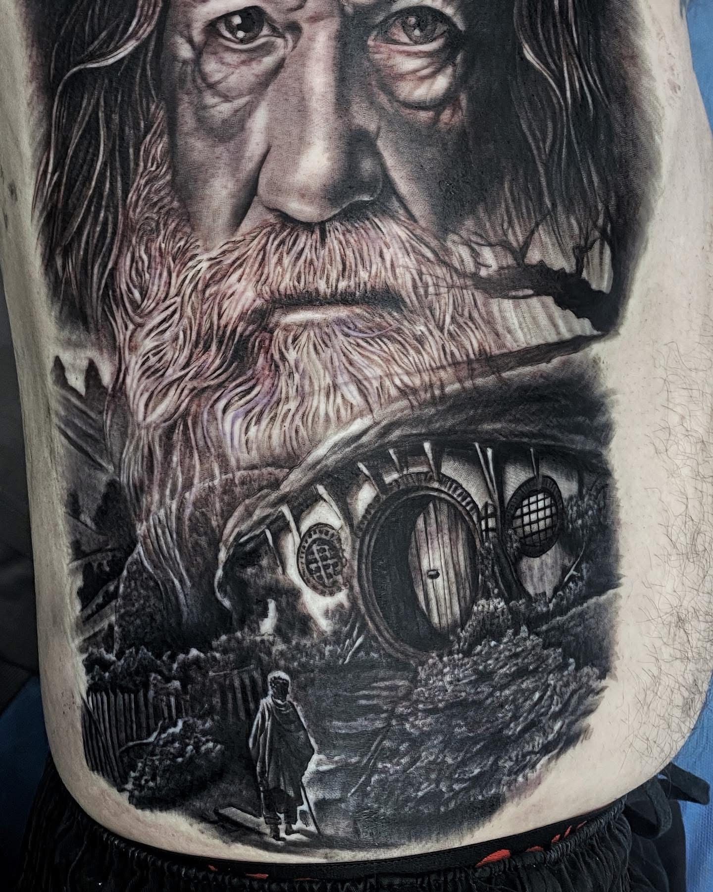 Tattoo of Gandalf, Hobbiton, and a figure walking. Black and grey shading. — Whitsunday Tattooing Airlie Beach in Whitsundays, QLD