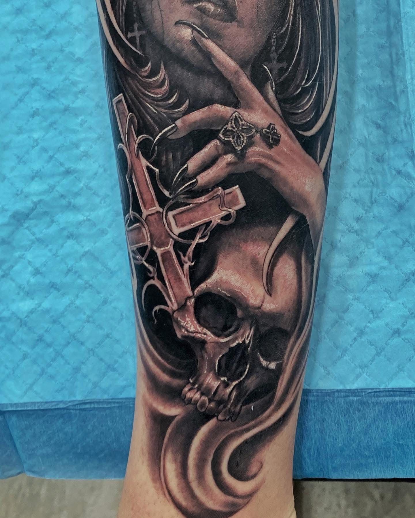 Tattoo of woman's face, hand with ring, cross, and skull in grayscale on an arm. — Whitsunday Tattooing Airlie Beach in Whitsundays, QLD