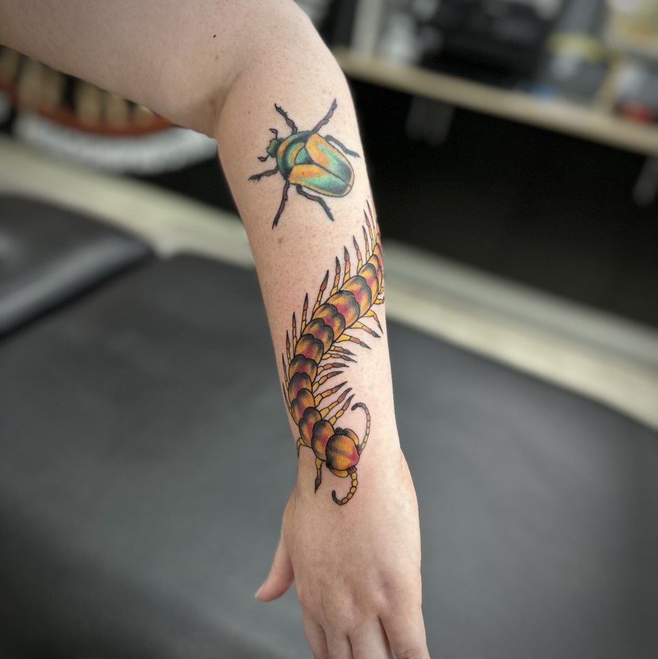 Tattoo of a green beetle and a brown and orange centipede on a person's forearm. — Whitsunday Tattooing Airlie Beach in Whitsundays, QLD