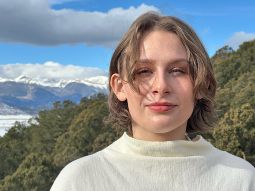Mel Garvin with short brown hair, smiling in front of snow-capped mountains and a blue sky.