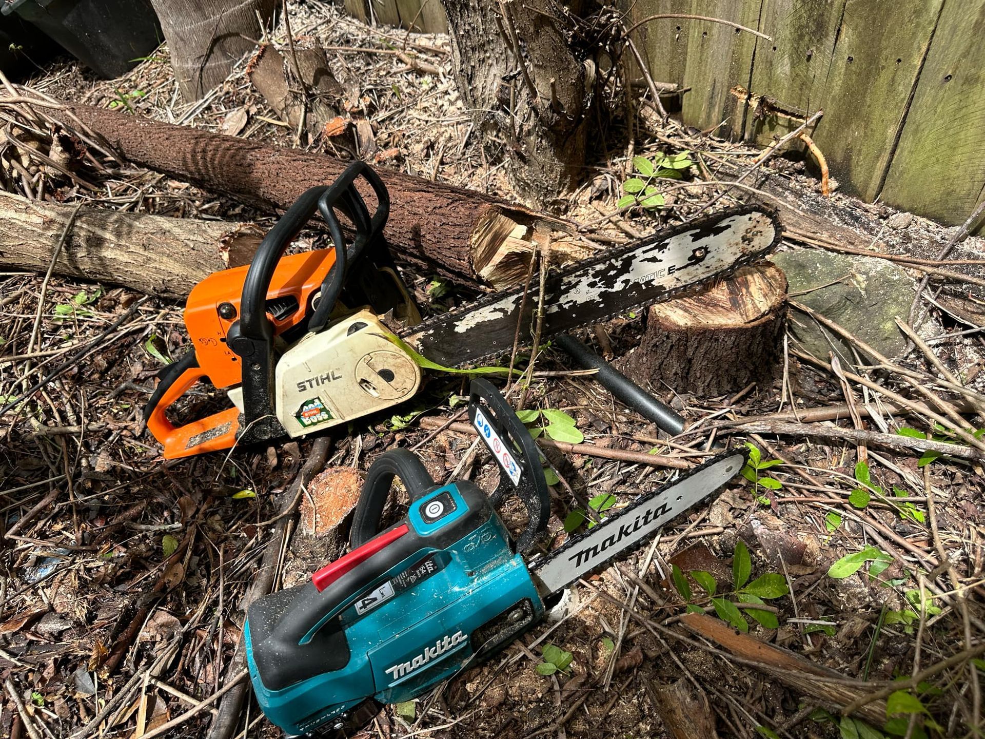 Two chainsaws are sitting on top of a tree stump | MowAbility Garden Services Gold Coast