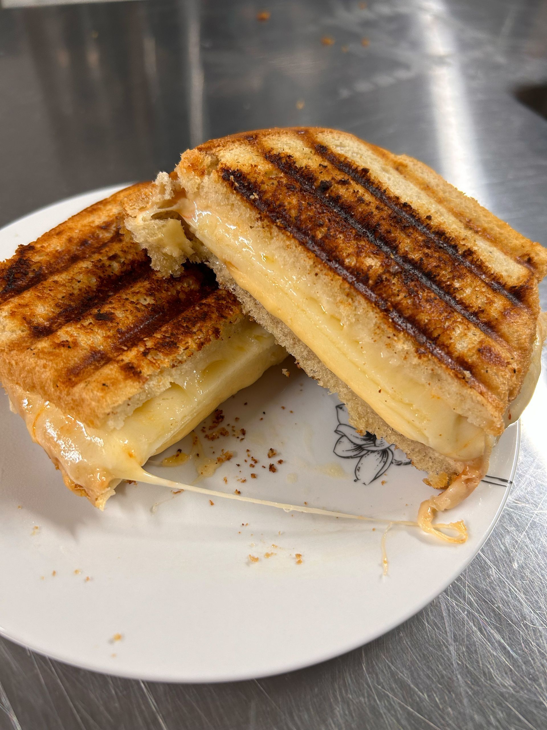 A grilled cheese sandwich is cut in half on a white plate.