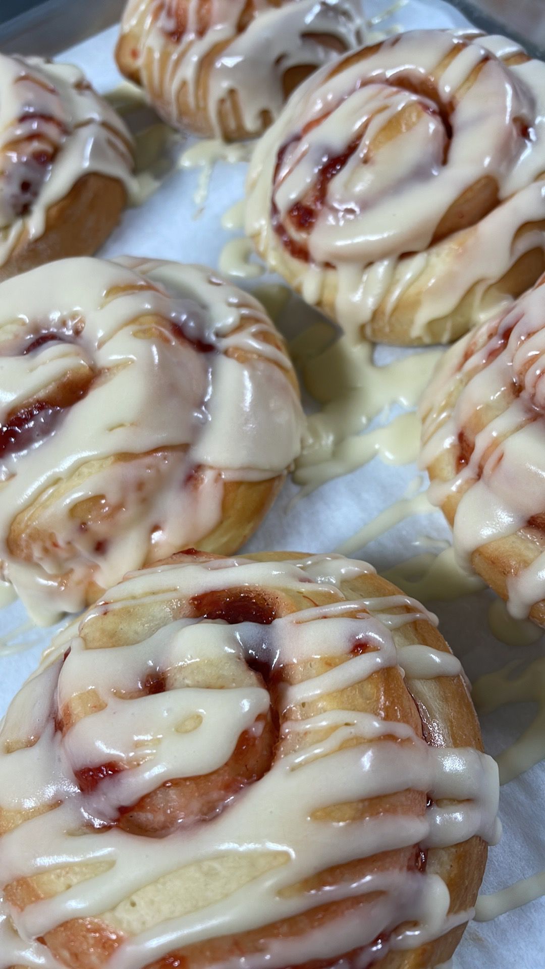 A bunch of cinnamon rolls with icing on them are sitting on a table.