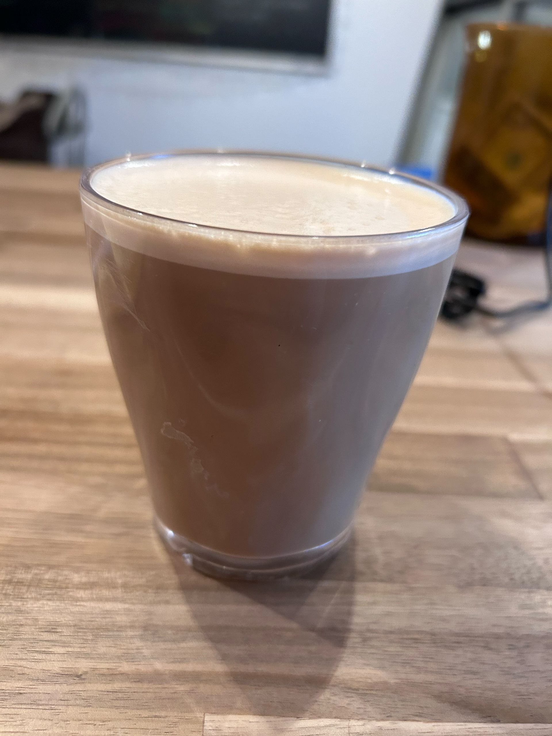 A cup of coffee is sitting on a wooden table.