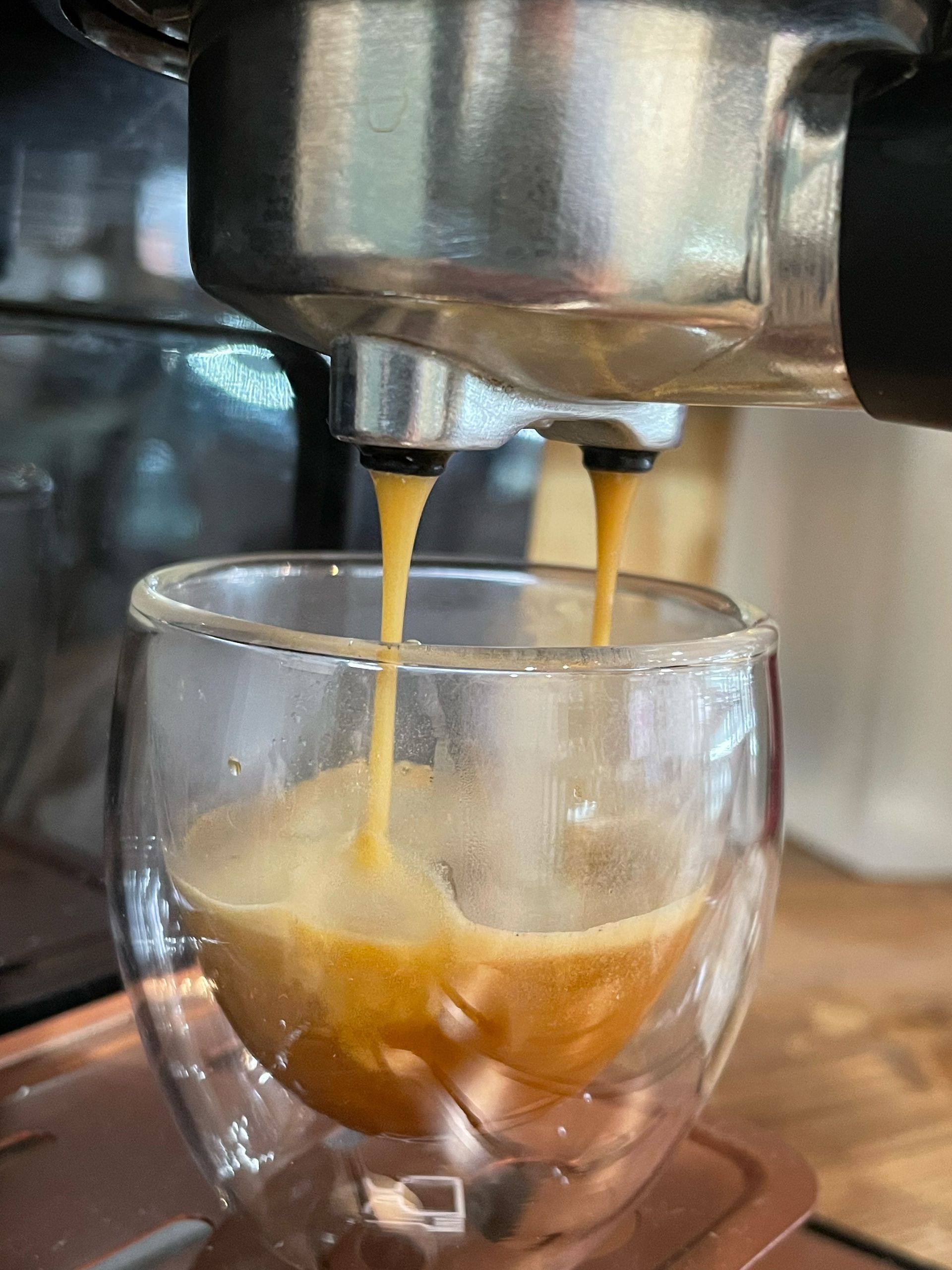 A close up of a coffee being poured into a glass cup.