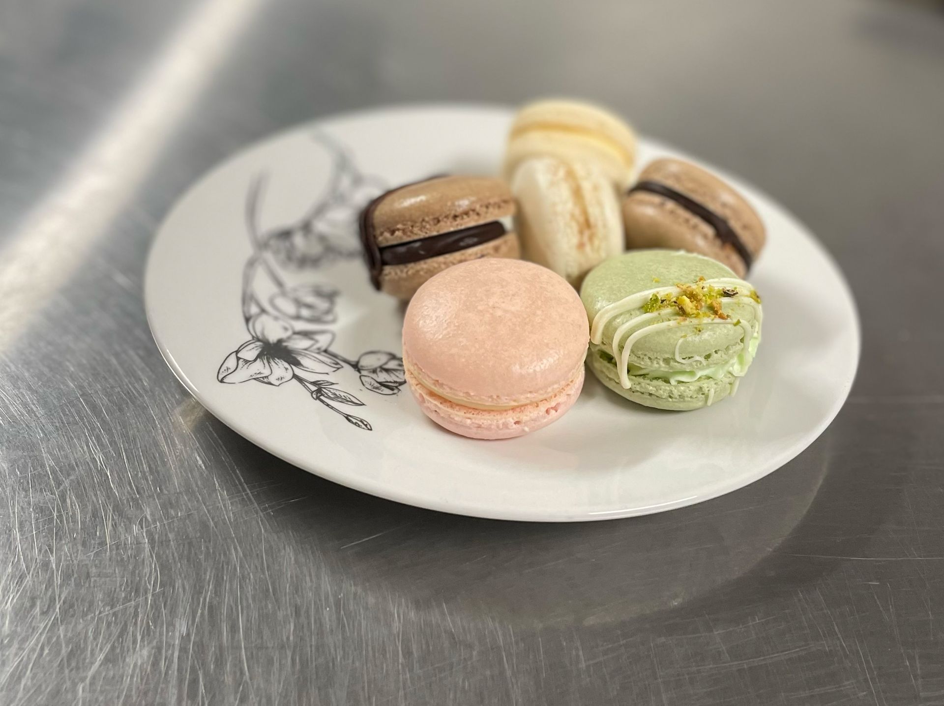 A white plate topped with a variety of macarons on a table.
