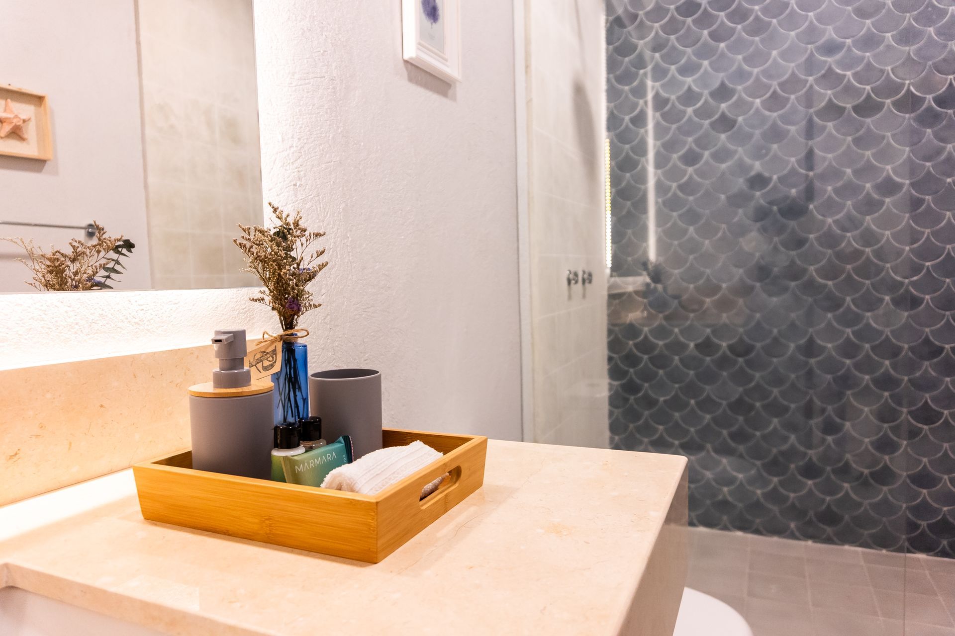 Dormitorio moderno con cama blanca, mesitas de noche flotantes y cabecero decorativo. Detalle de guijarros en el suelo.