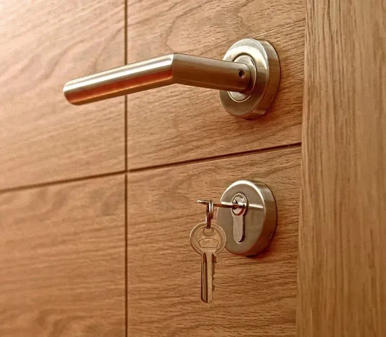 Door with Silver Handle and Key in The Lock, Set in A Wood Panel Door — Nq Locksmiths in Bowen, QLD