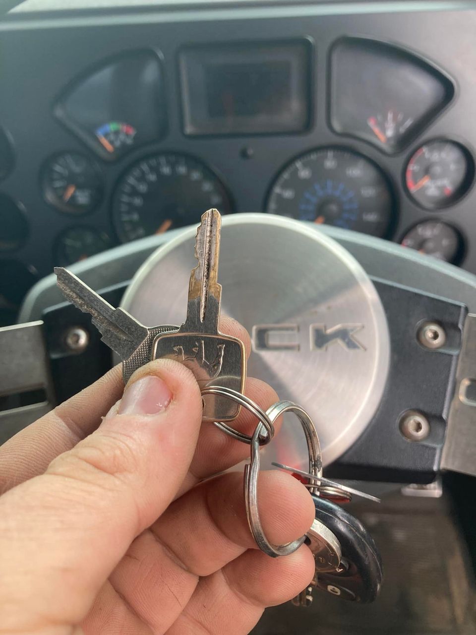 Hand Holding Truck Keys with Steering Wheel and Dashboard in The Background — Nq Locksmiths In Kirwan, QLD
