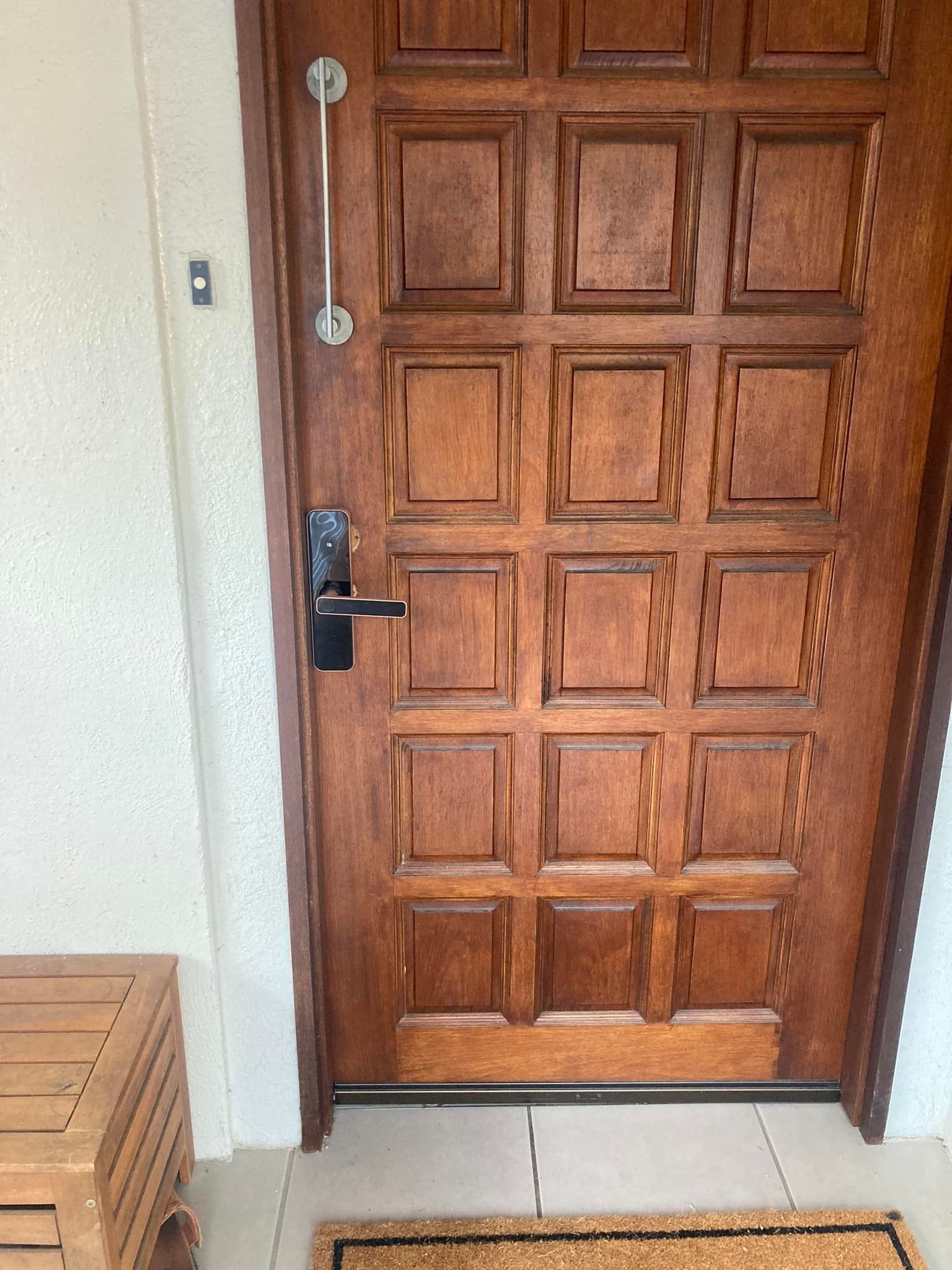 Wooden Door with Square Panels, Black Handle, and Long Silver Pull, Next to A White Wall — Nq Locksmiths In Kirwan, QLD