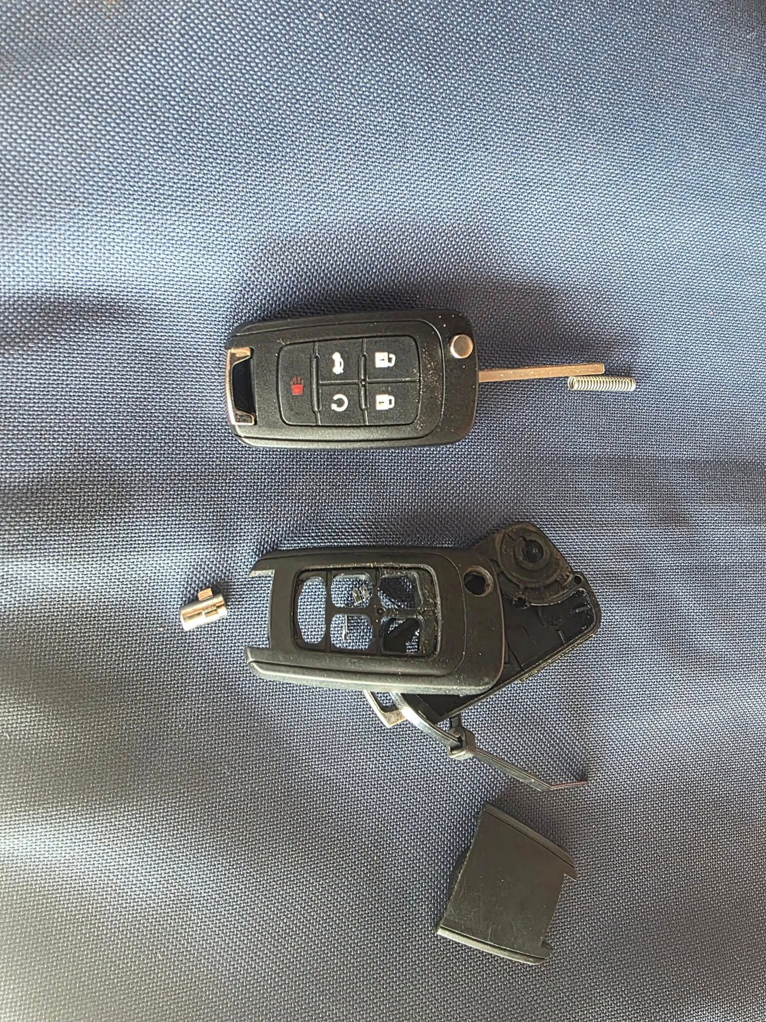 Broken Car Key Remote Lying on A Blue Surface, with Separated Components — Nq Locksmiths In Kirwan, QLD
