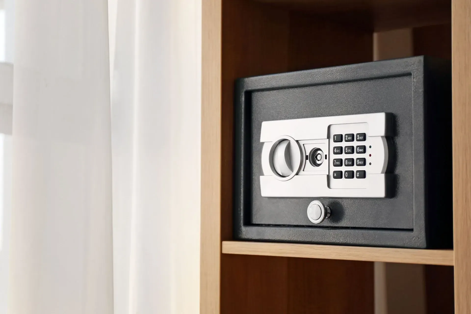Dark Gray Digital Safe in A Wooden Shelf, Next to A White Curtain — Nq Locksmiths in Ingham, QLD