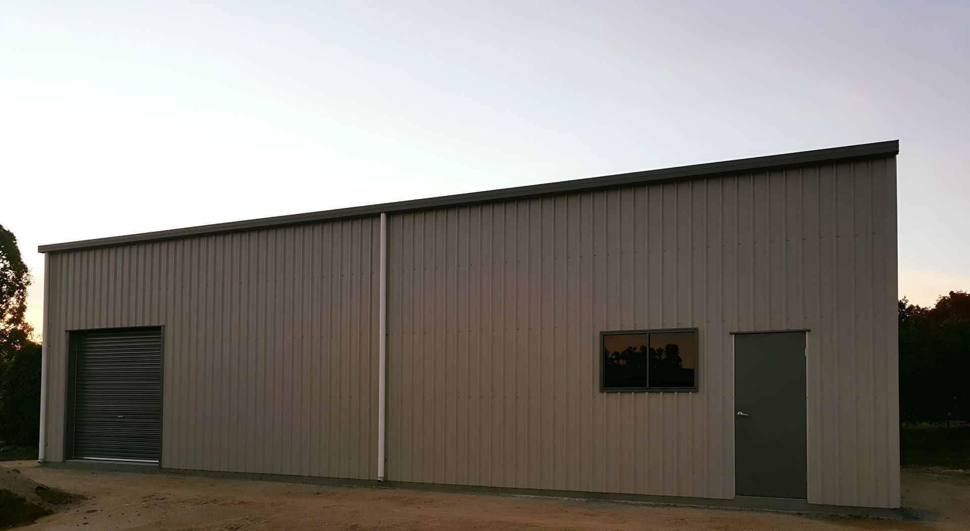 a Large Metal Building With a Garage Door and a Window — Mareeba Sheds & Gas In Mareeba, QLD=