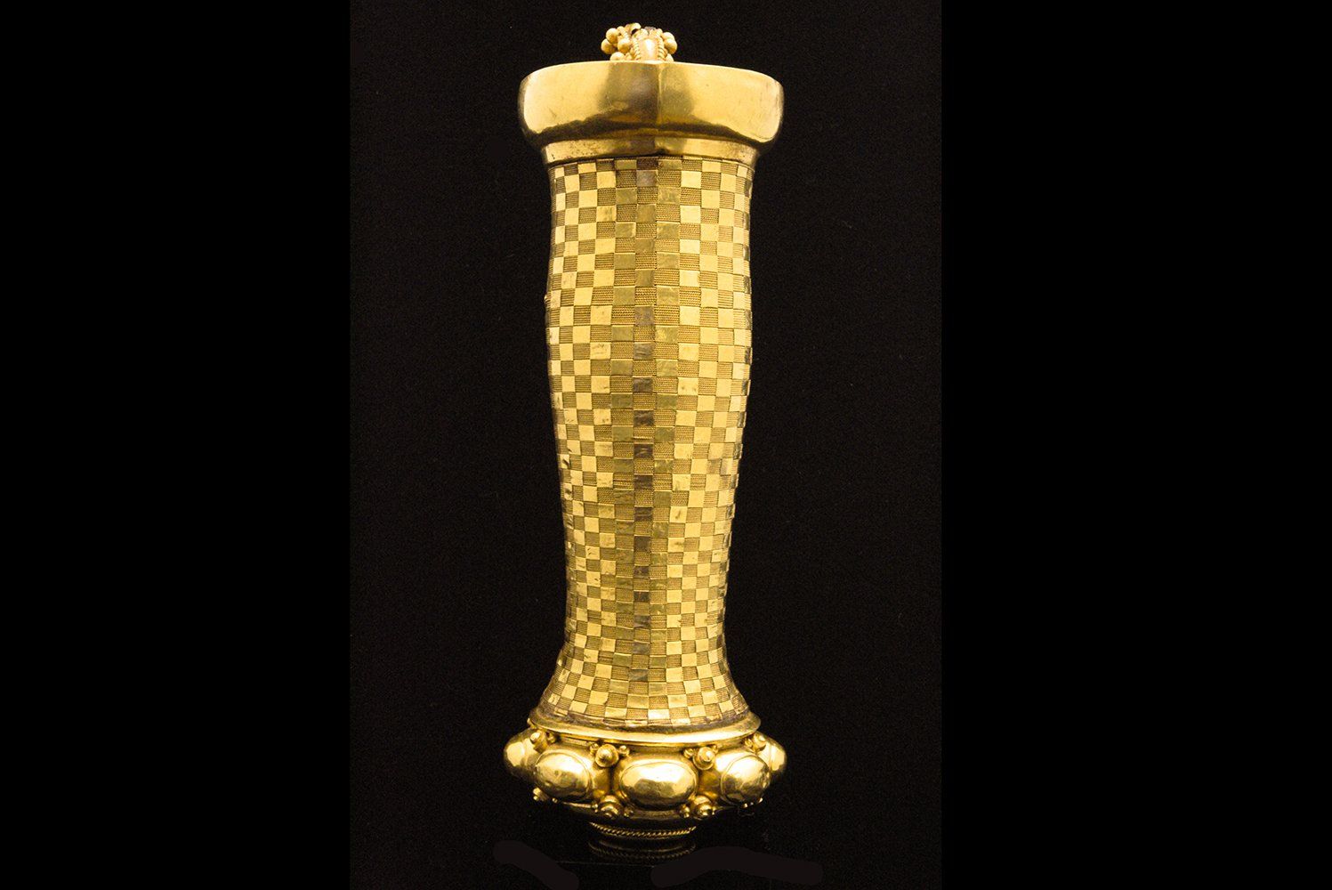 Le corps de la poignée est composé de fil d'or tissé avec des bandelettes de la même matiere. L'échiquier ainsi créé rappelle celui des sarong et de la dualité qui compose chaque chose. Dans la cupule superieur une sorte d'anse figure lecorps d'un petit dragon posé sur un lotus. Magnifique poignée royale de Bali 18ème siécle ou plus tôt.