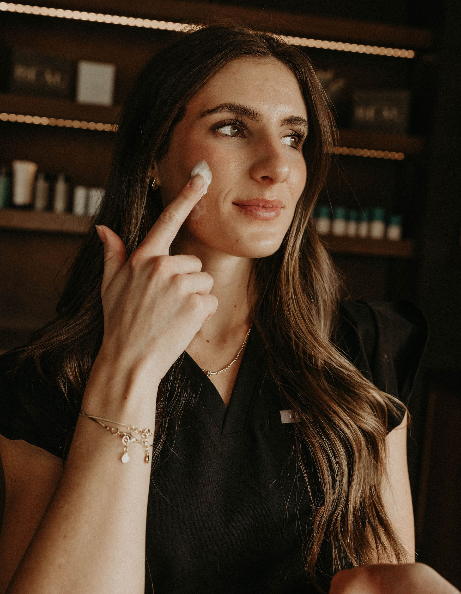 A woman is applying a serum to her face.