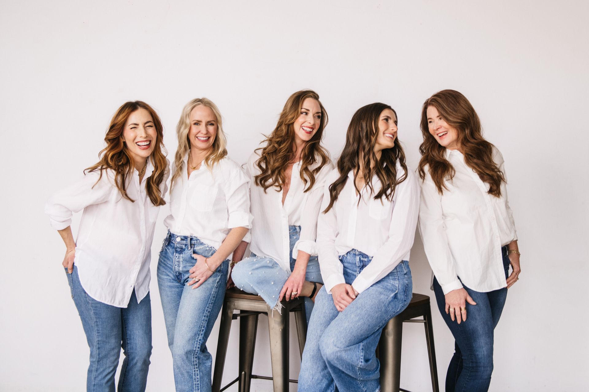 A group of women are posing for a picture while sitting on stools.