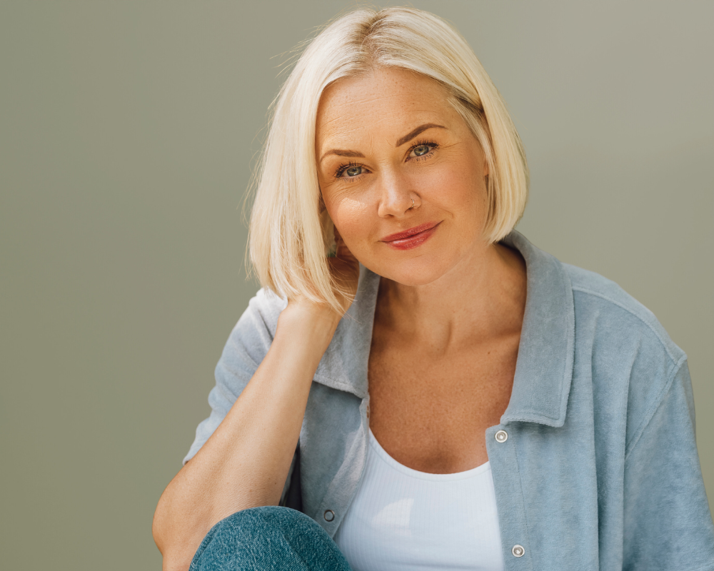 A woman in a white t-shirt and blue jeans is giving an ok sign.