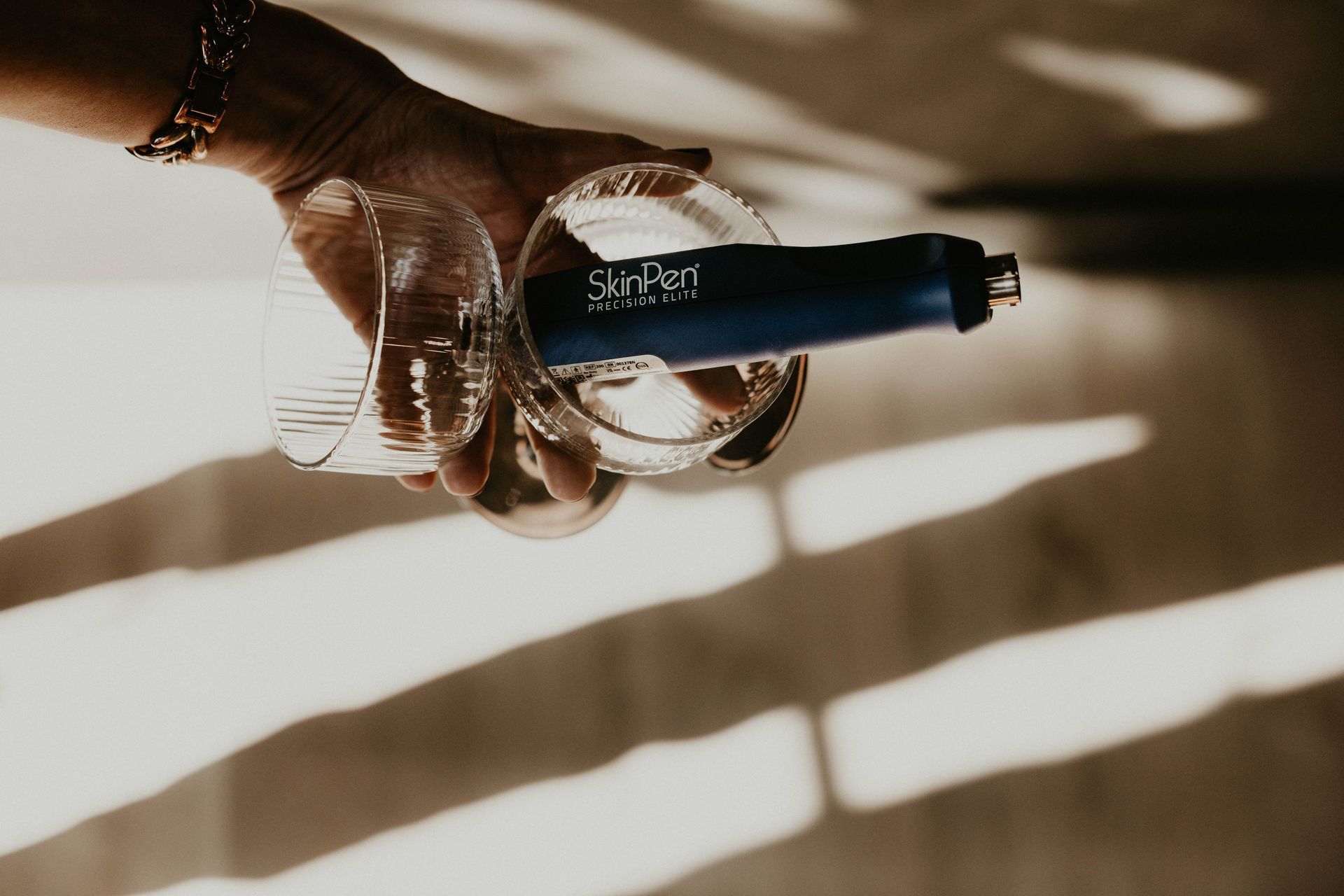 Hand pouring liquid from blue bottle into two clear glasses.