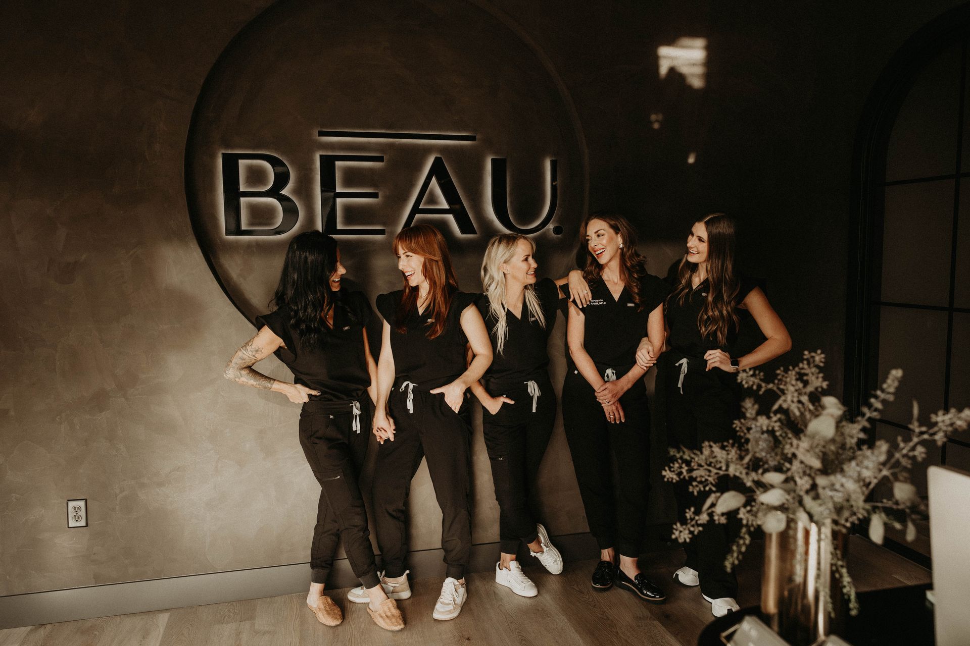 A group of women are posing for a picture while sitting on stools.