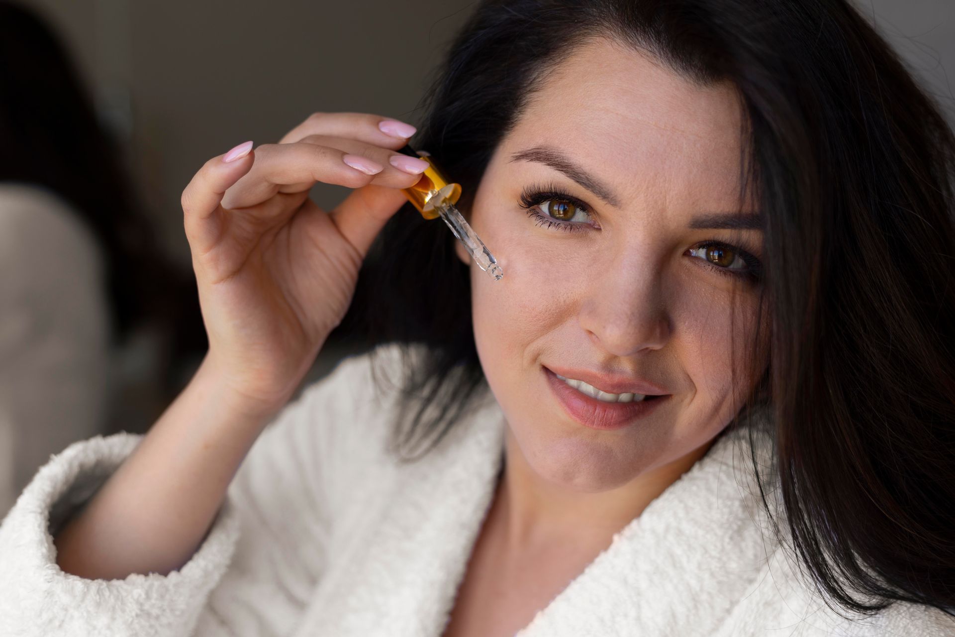 A woman is applying a serum to her face.