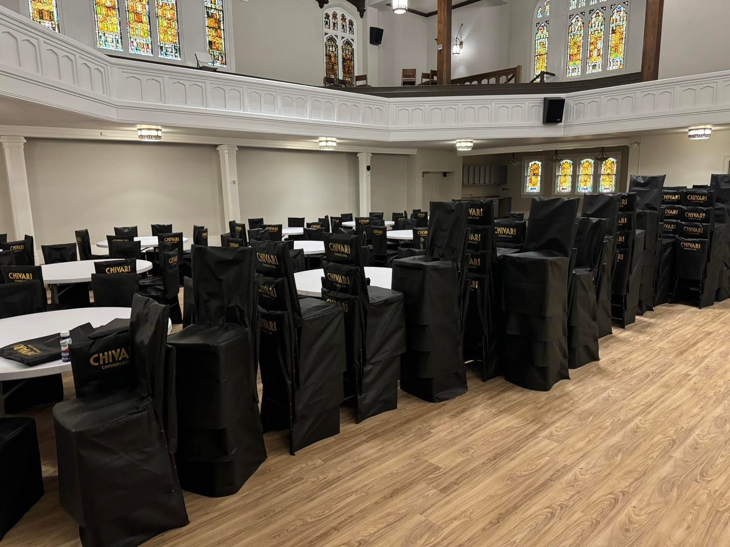 A large room filled with tables and chairs covered in black covers.