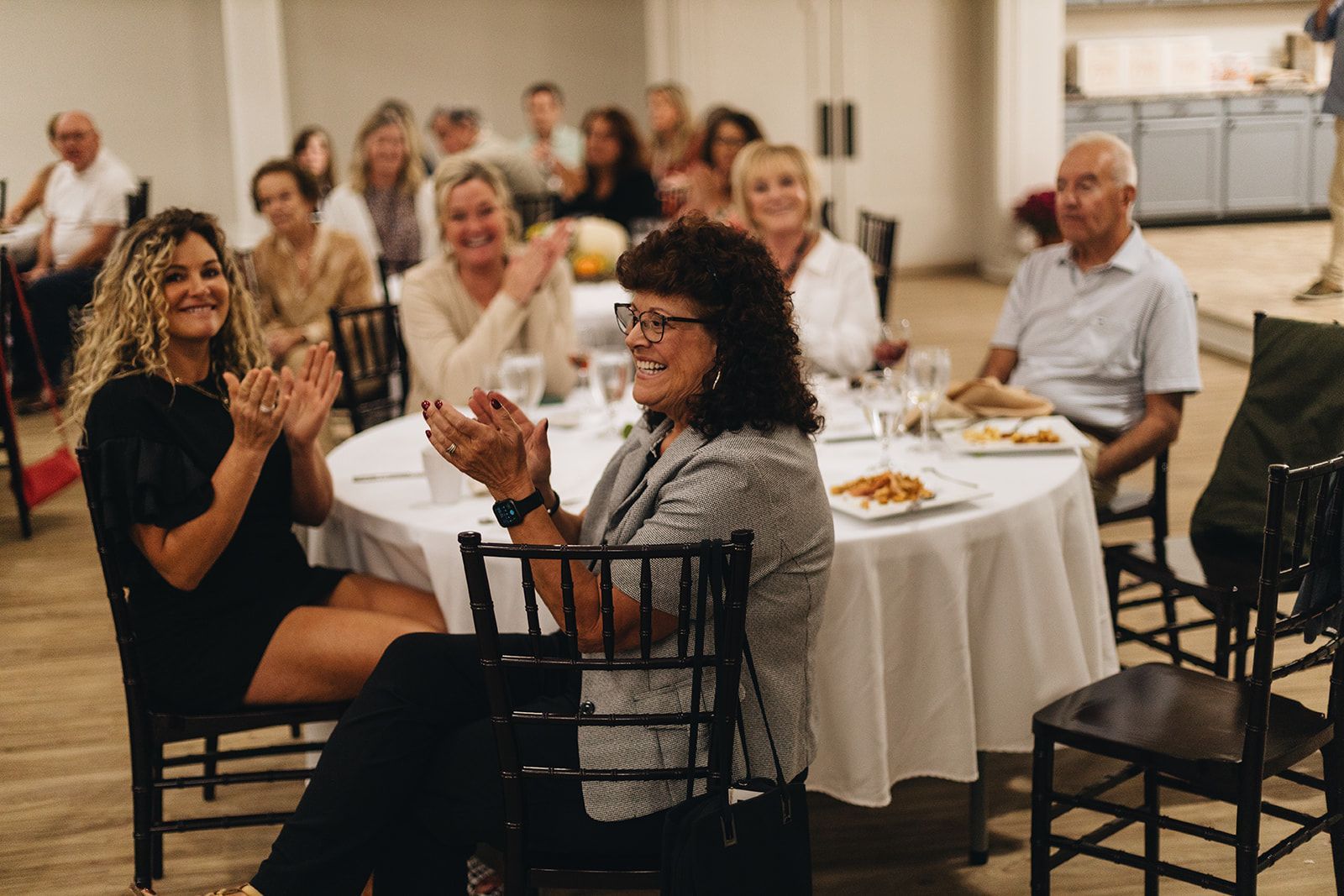 A large room filled with tables and chairs covered in black covers.